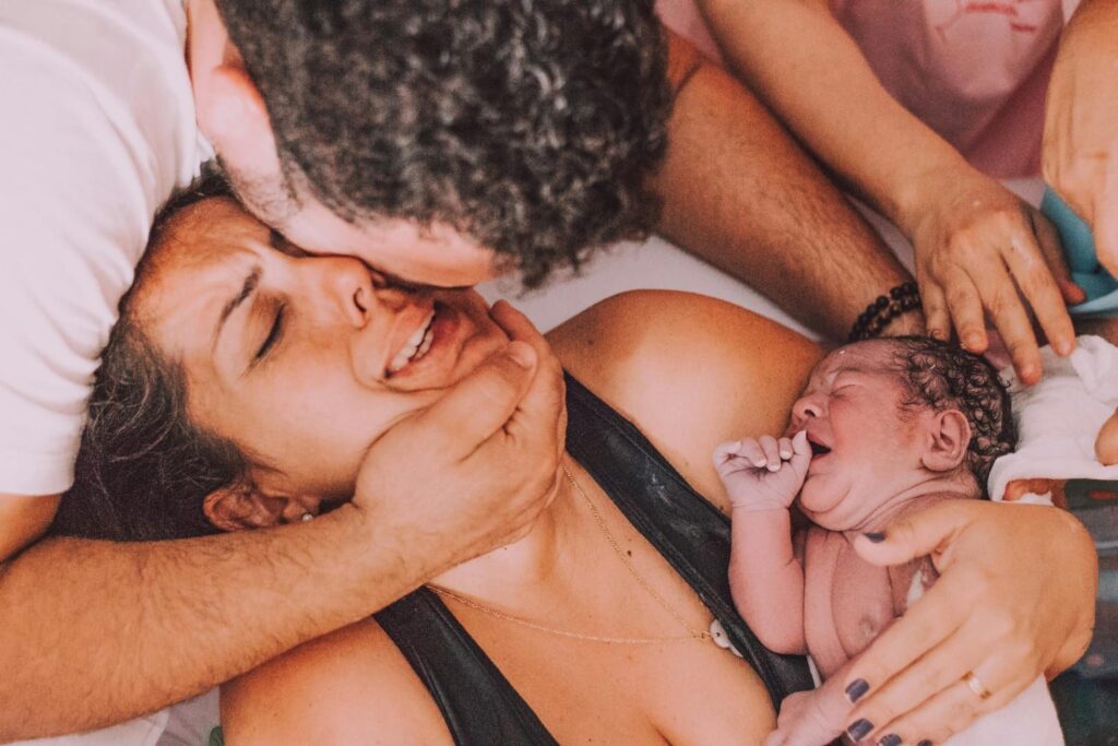 Jeune maman après son accouchement à domicile avec son nouveau-né et son compagnon