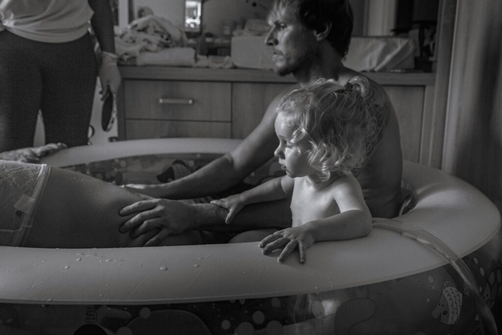 Papa qui soutient sa partenaire lors d'un accouchement à domicile